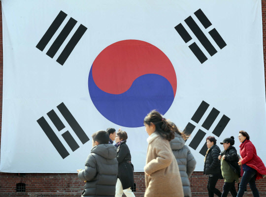 3·1절을 하루 앞둔 28일 서울 서대문구 서대문형무소역사관을 찾은 시민들이 대형 태극기 앞을 걸어가고 있다.